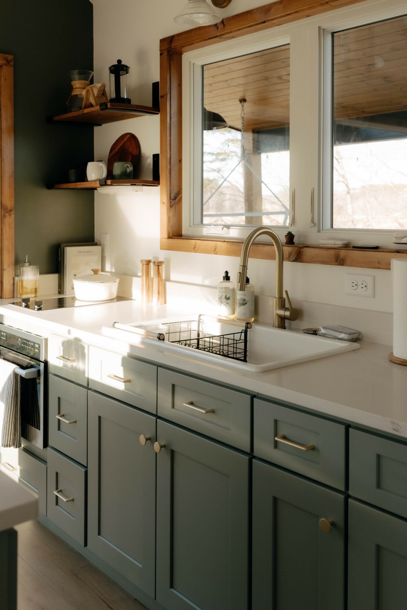 Kitchen with blue cabinets, white countertop, window, and sink with faucet, sunlight streaming in.
