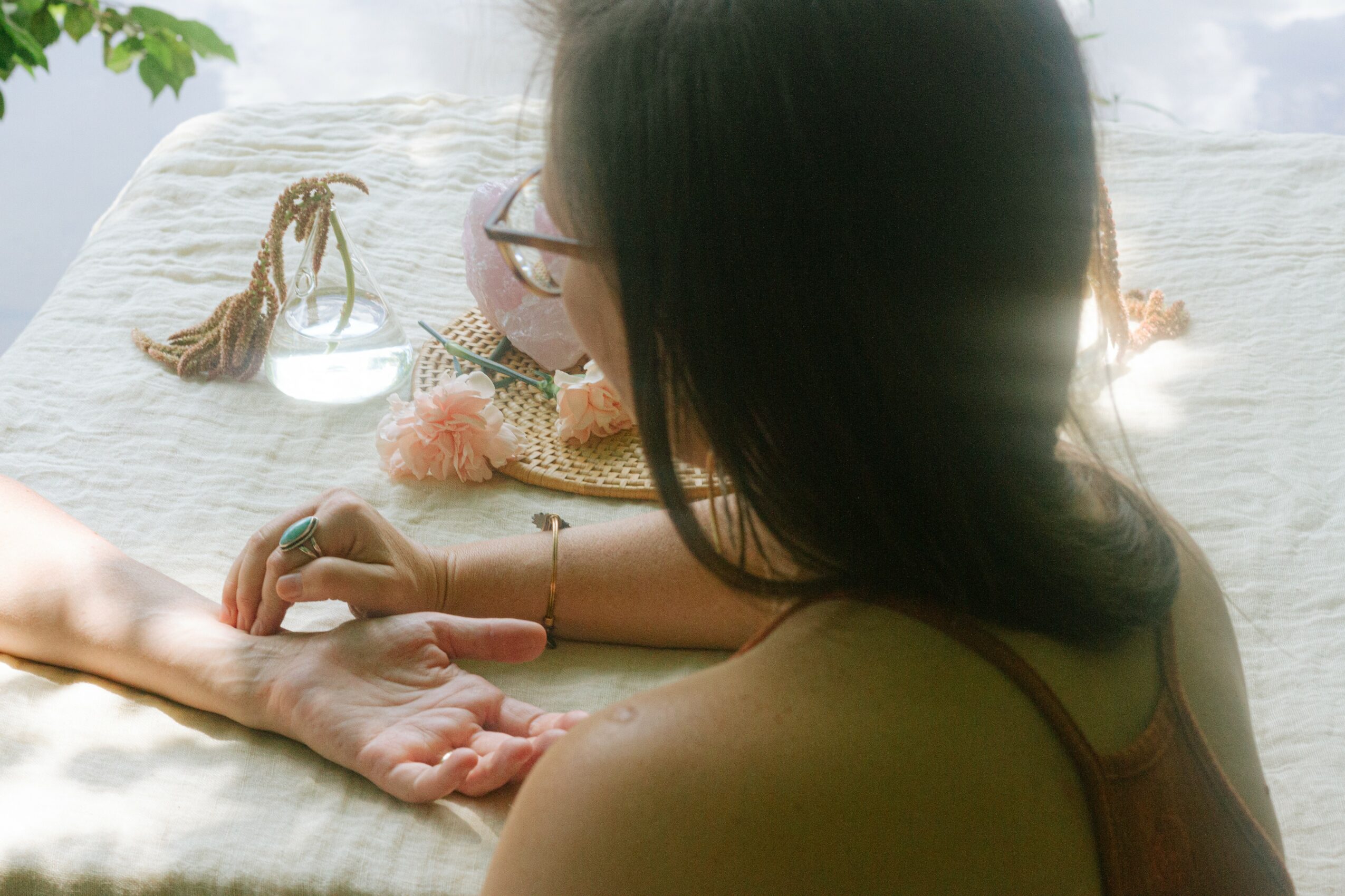 Person with dark hair and glasses holding a hand, with a child nearby, on a white surface outdoors.